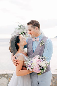 bride and groom are hugging and looking at each other on the pier