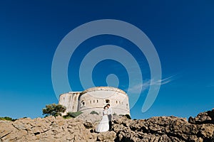 bride and groom are hugging near the Arza fortress on the Mamula island