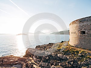 bride and groom are hugging near the Arza fortress on the Mamula island