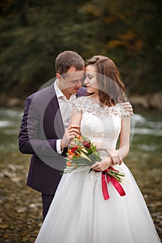 Bride and groom hugging near the river