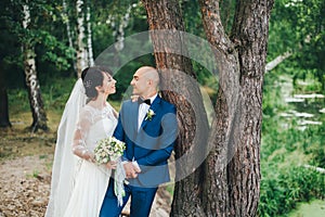 The bride and groom hugging near a tree