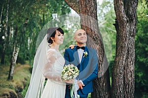 The bride and groom hugging near a tree