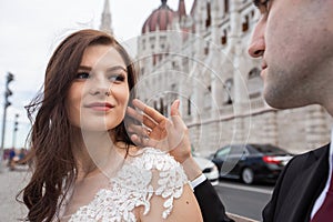 Bride and groom hugging in the old town street. Wedding couple sit in Budapest near Parliament House. Caucasian happy