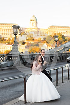 Bride and groom hugging in the old town street. Wedding couple walking on Szechenyi Chain Bridge, Hungary. Happy
