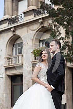 Bride and groom hugging in the old town street. Wedding couple walks in Budapest near Parliament House. Caucasian happy