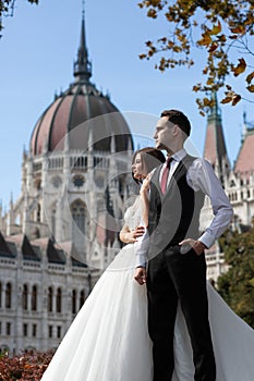 Bride and groom hugging in the old town street. Wedding couple walks in Budapest near Parliament House. Caucasian happy