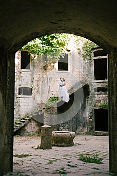 bride and groom are hugging on the stairs of the ancient abandoned Arza fortress on the Mamula island