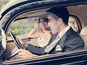 Bride and groom inside a classic car, vintage tone
