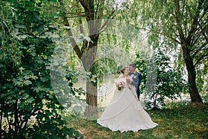 The bride and groom are kidnapped in nature, strolling in the park near the pond and listening to the singing of birds.