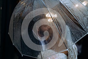 bride and groom kiss, blocking umbrella. a couple at a wedding in the rain. wedding in the rain