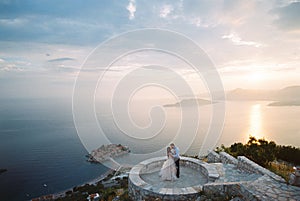 Bride and groom kiss on the observation deck over the Sveti Stefan island. Montenegro