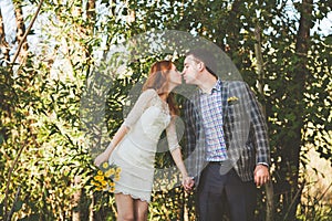 The bride and groom kissing each other in the forest