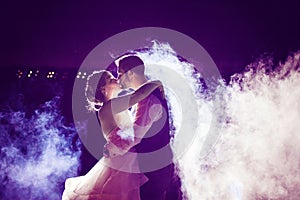 Bride and Groom kissing in fog with purple night sky