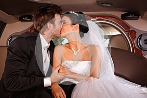 Bride and groom kissing in limo