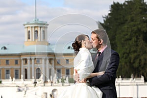 Bride and groom kissing near palace