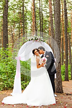 Bride and groom kissing near the wedding arch