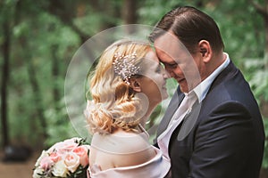 Bride and groom kissing in the summer forest