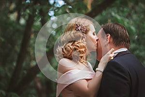 Bride and groom kissing in the summer forest