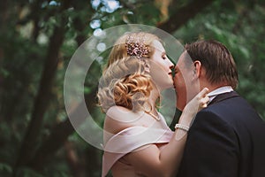 Bride and groom kissing in the summer forest