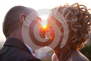 Bride and groom kissing at sunset