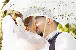Bride and groom kissing under an umbrella