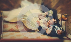 Bride and groom lay carelessly on the old sofa photo