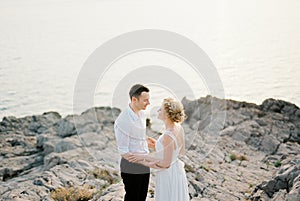 Bride and groom look into each other eyes, hugging forearms