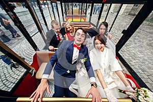 Bride and groom look funny sitting with friends in a tourist train