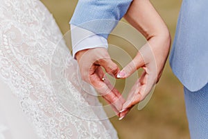 The bride and groom make heart hands