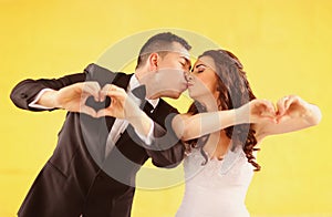 Bride and groom making heart shape with their hands