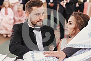 Bride and groom making oaths and priest holding their hands on