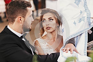 Bride and groom making oaths and priest holding their hands on