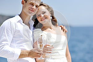 Bride and groom making a toast by the sea in wedding day