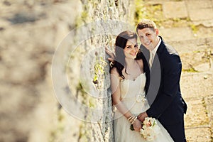 Bride and groom near old ruined castle wall