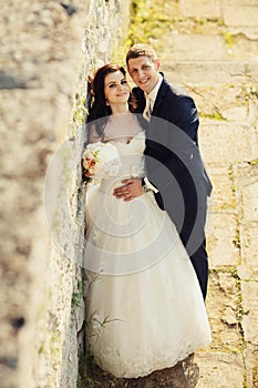 Bride and groom near old ruined castle wall