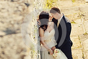 Bride and groom near old ruined castle wall