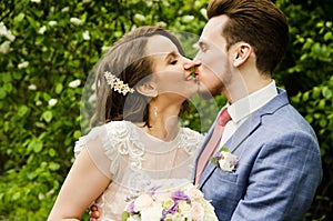 Bride and groom in a park kissing.couple newlyweds bride and groom at a wedding in nature green forest are kissing photo portrait.