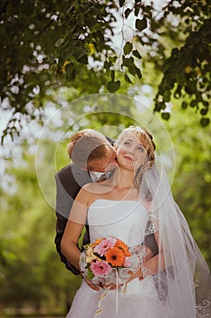 Bride and groom in a park kissing.couple newlyweds bride and groom at a wedding in nature green forest are kissing photo