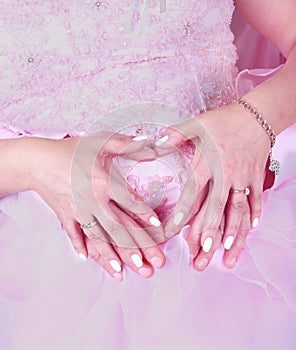 Bride and groom in pink holding hands in the form of a heart