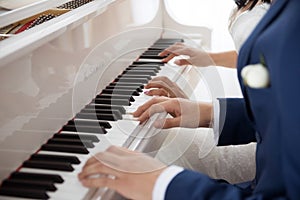 The bride and groom play the piano in two hands