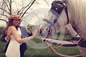 Bride and groom playing with white horse