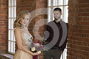 Bride and groom pose near window and vintage brick wall