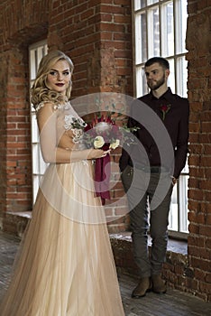 Bride and groom pose near window and vintage brick wall