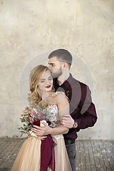 Bride and groom pose near window and wall