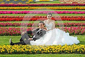 Bride and groom posing on lawn with flowers