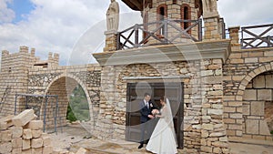 Bride and groom posing for photos and videos near the magnificent castle and stone wall