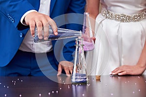 Bride and groom pouring colorful bead into the bottle. Sand ceremony variation