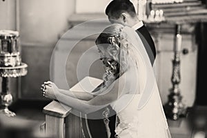 Bride and groom pray standing on the knees during an engagement