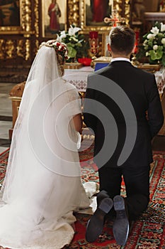 Bride and groom praying at wedding ceremony in church, handsome