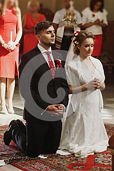 Bride and groom praying at wedding ceremony in church, handsome